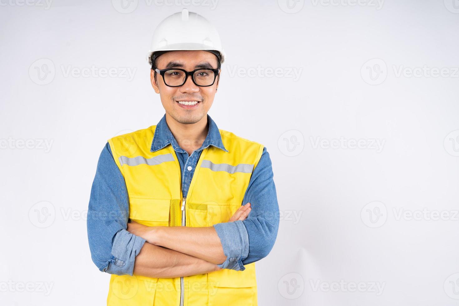 lächelnde junge asiatische Bauingenieur mit Helm Schutzhelm stehend auf isolierten weißen Hintergrund. Mechaniker-Service-Konzept. foto