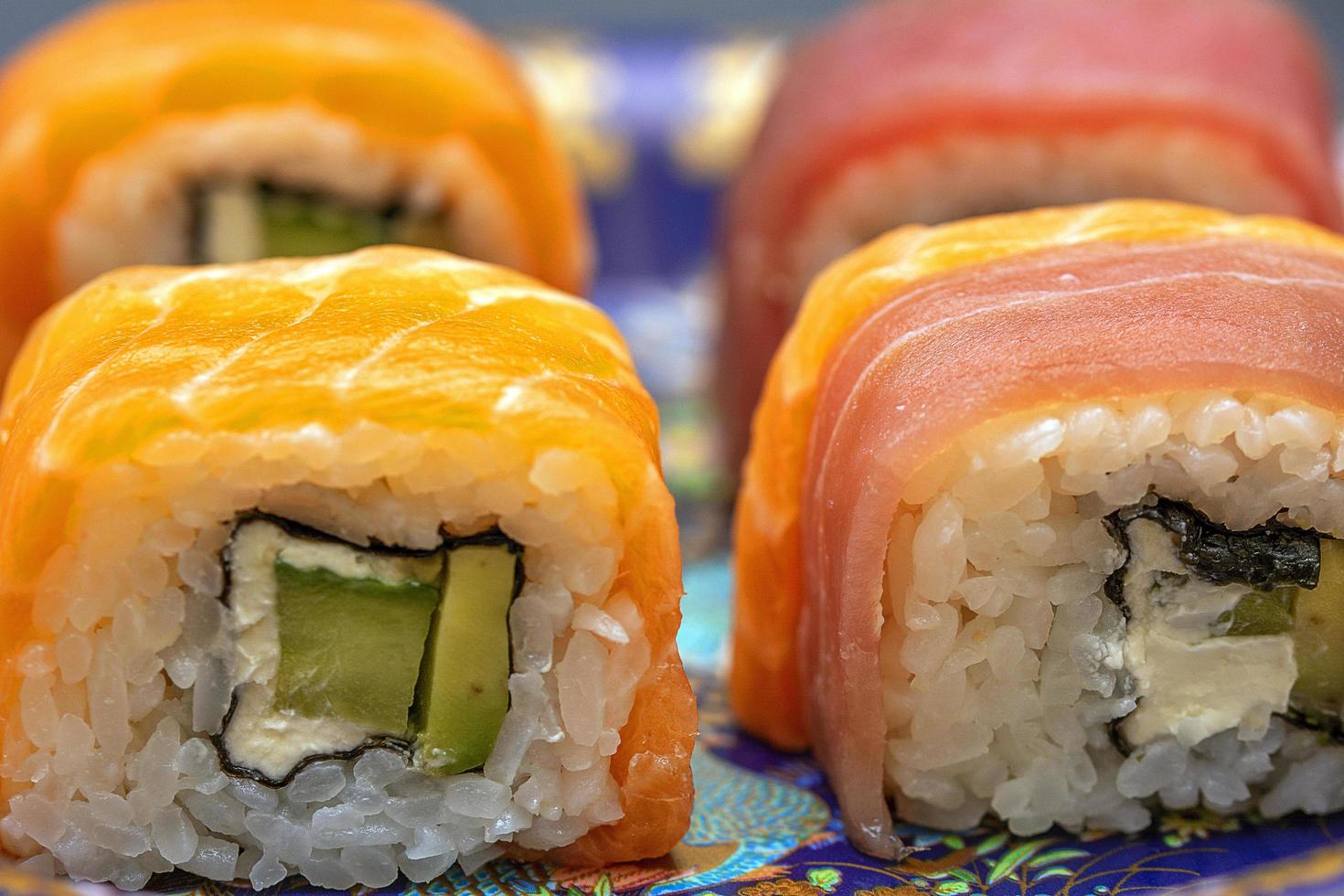 kalifornische Sushi-Rollen mit Avocado, Gurke und Käse umhüllt von Lachs und Thunfisch foto