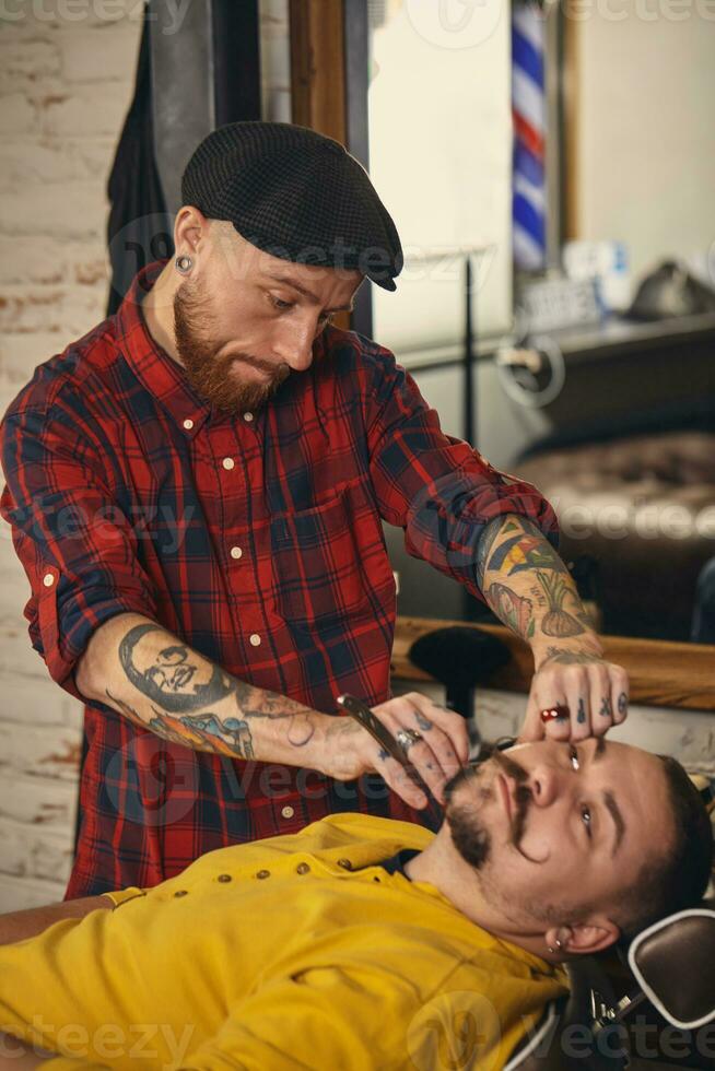 Klient während Bart Rasieren im Barbier Geschäft foto