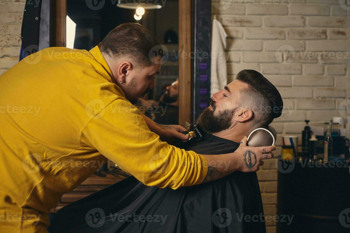 Klient mit groß schwarz Bart während Bart Rasieren im Barbier Geschäft foto