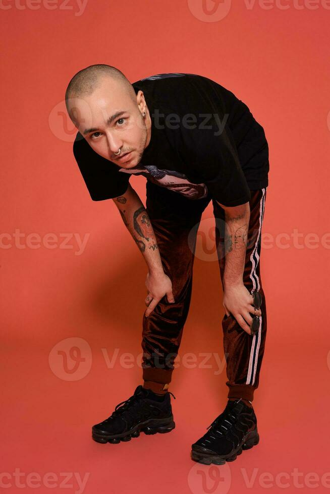 Studio Schuss von ein jung tätowiert kahl Mann posieren gegen ein Rosa Hintergrund. 90er Jahre Stil. foto