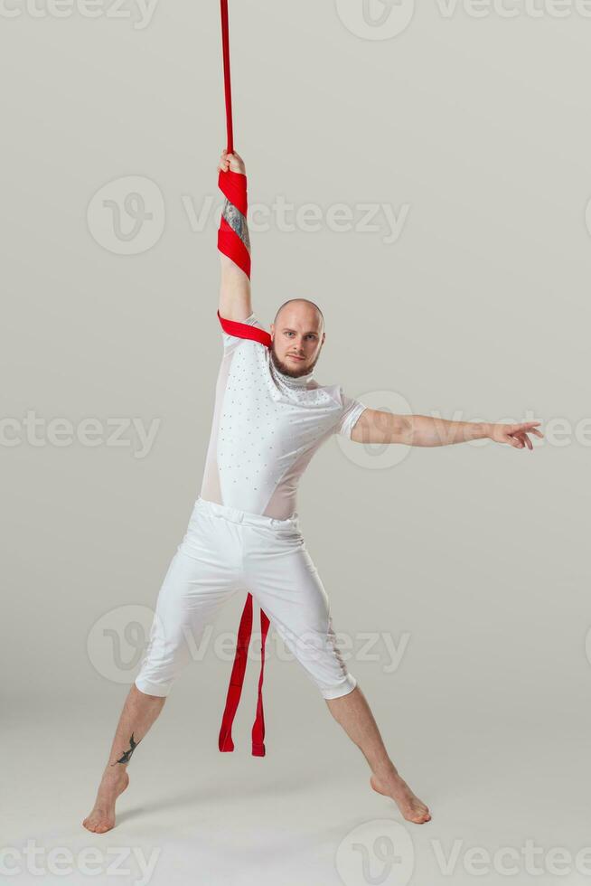 sportlich Mann im ein Weiß Sport passen ist durchführen ein akrobatisch Elemente im ein Studio. foto