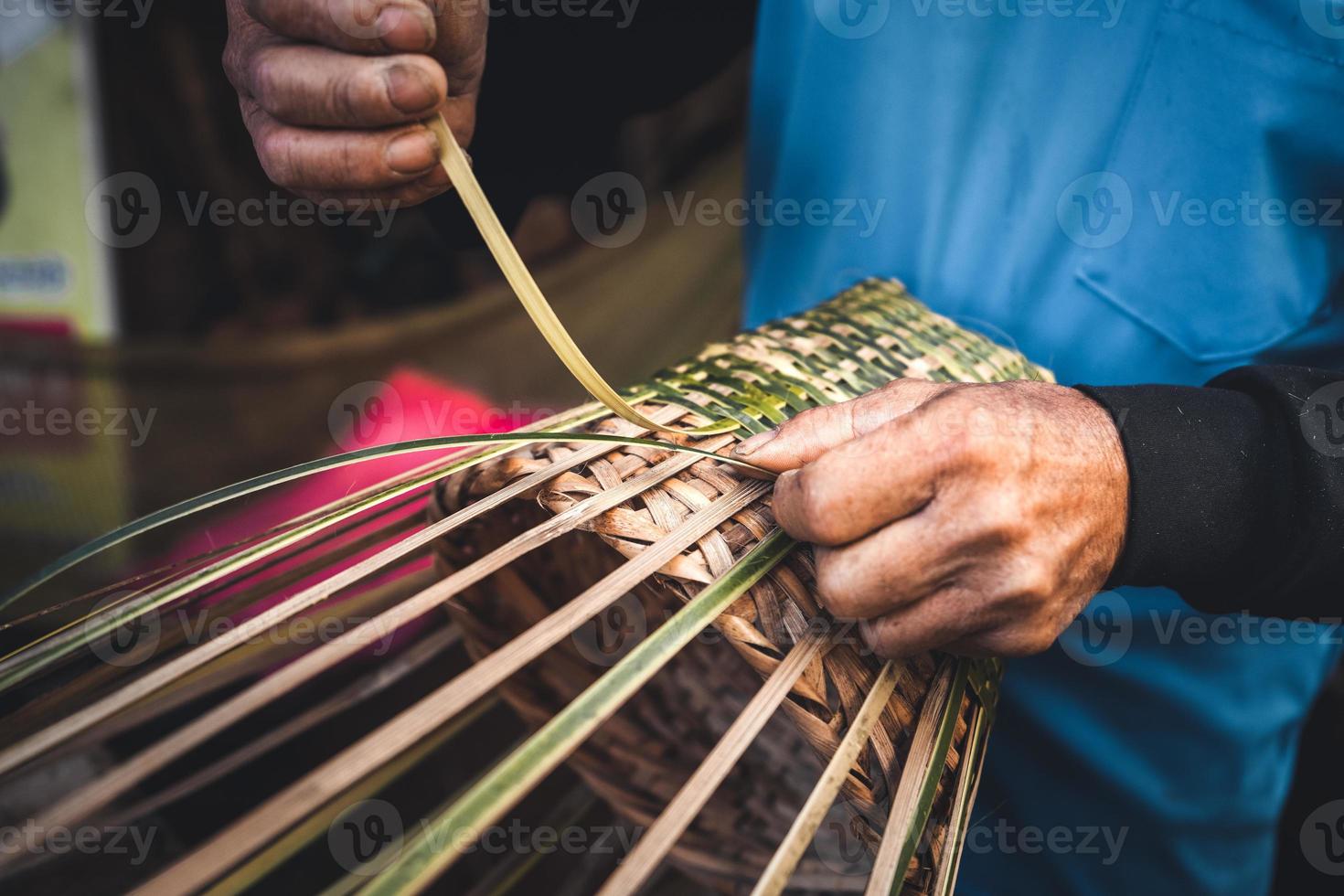 Hände, die zu Hause Bambuskörbe flechten foto