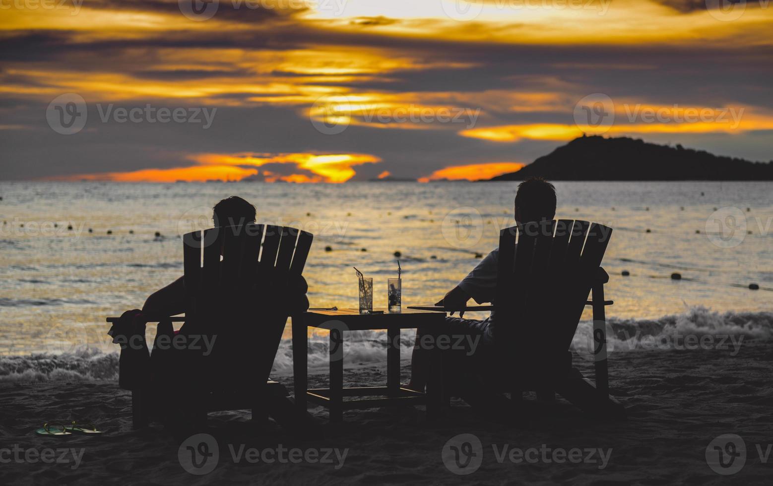 Silhouette paar entspannen Stuhl am Strand. foto