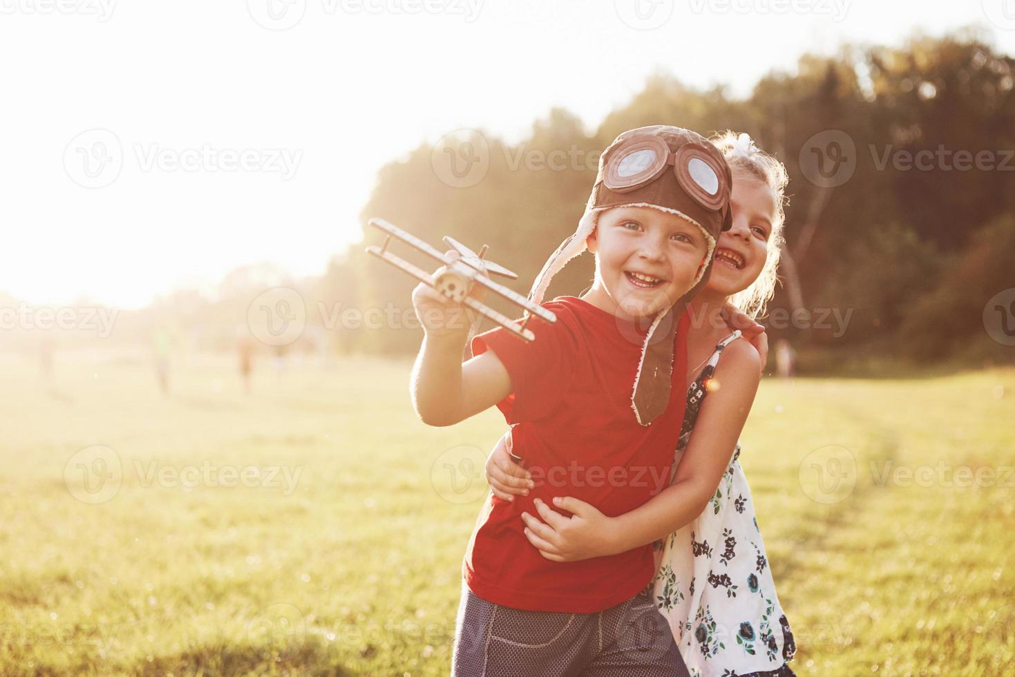 Bruder und Schwester spielen zusammen. zwei Kinder spielen mit einem Holzflugzeug im Freien foto