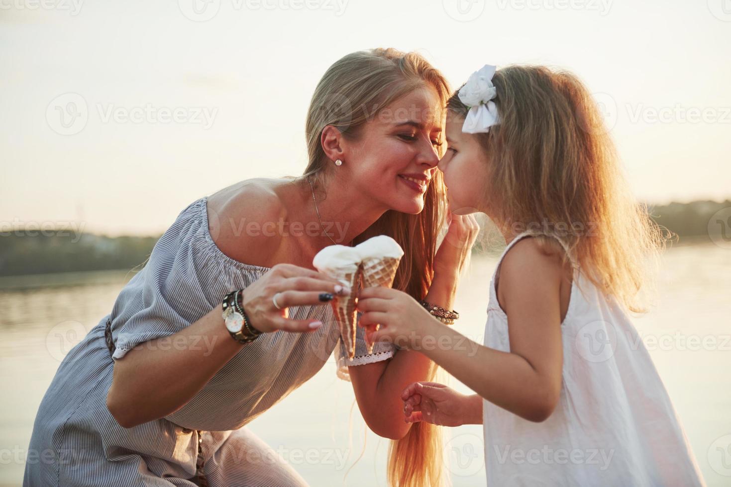 Mutter und Kind essen bei Sonnenuntergang Eis im Park. foto