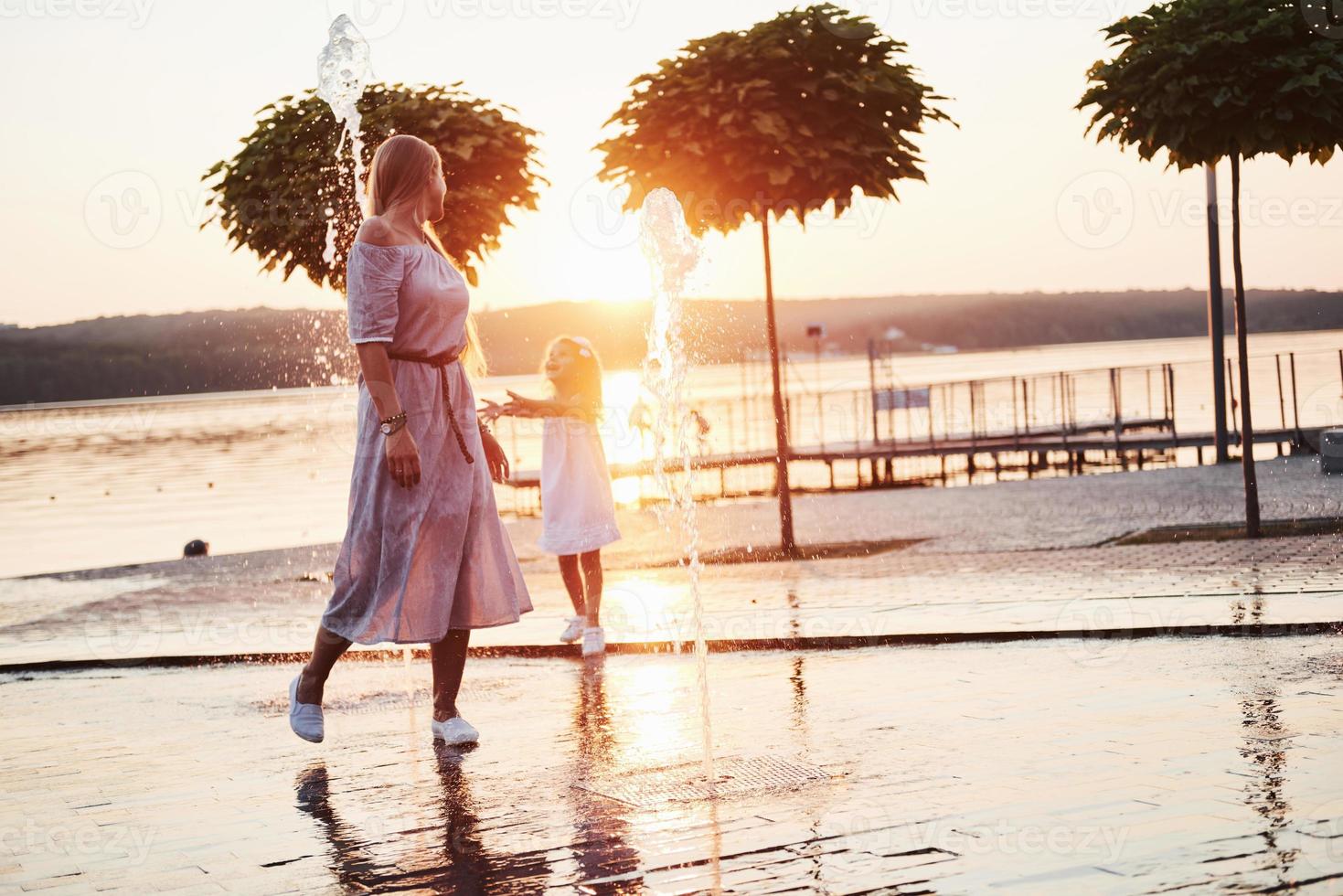 Mutter mit Baby in der Nähe des Brunnens bei Sonnenuntergang foto