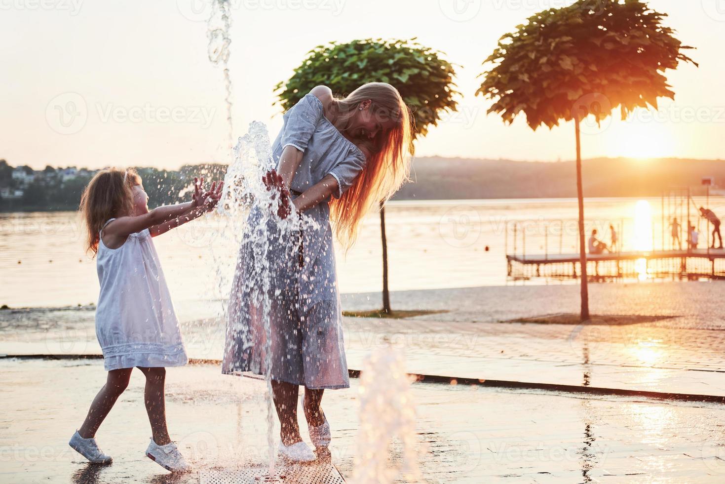 eine Frau, die bei Sonnenuntergang mit einem Kind am Meer im Park spielt foto