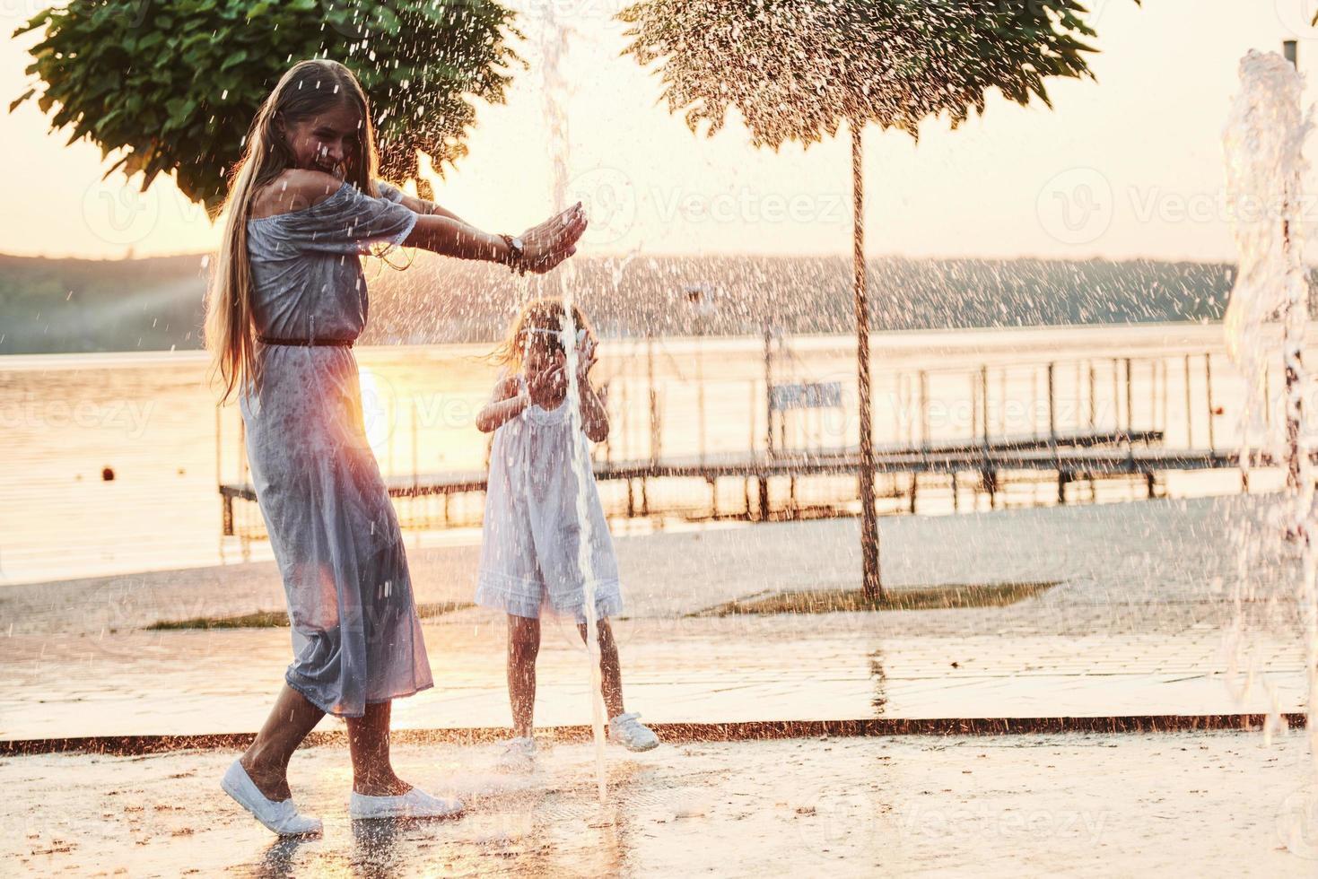 Mutter mit Baby in der Nähe des Brunnens bei Sonnenuntergang foto