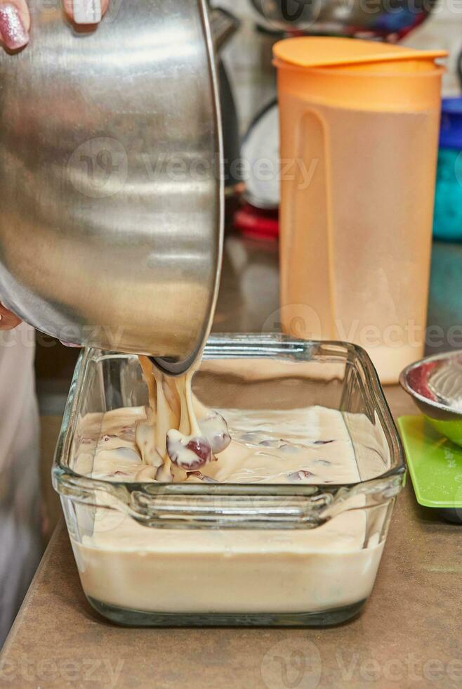 das Koch gießt das Teig zum Herstellung Kirsche Kuchen im ein transparent bilden in das Ofen. Lasst uns bereiten ein köstlich hausgemacht Dessert foto