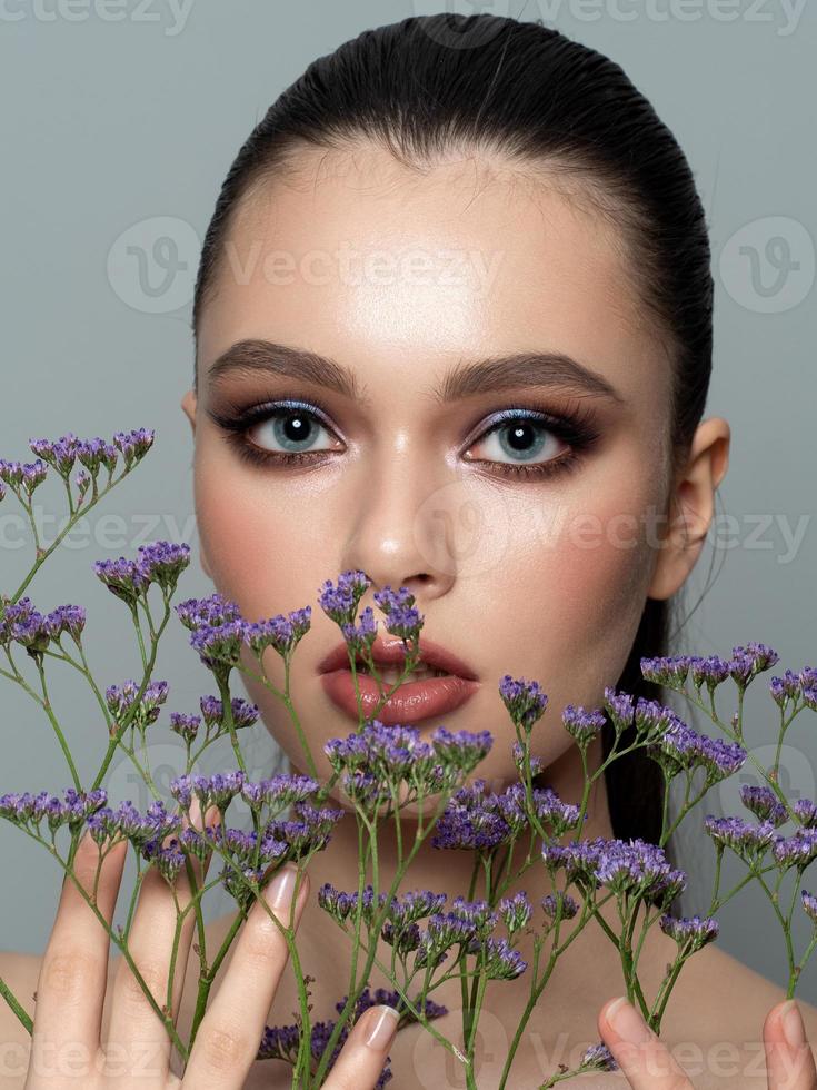 Porträt der jungen schönen Frau mit Blumen foto