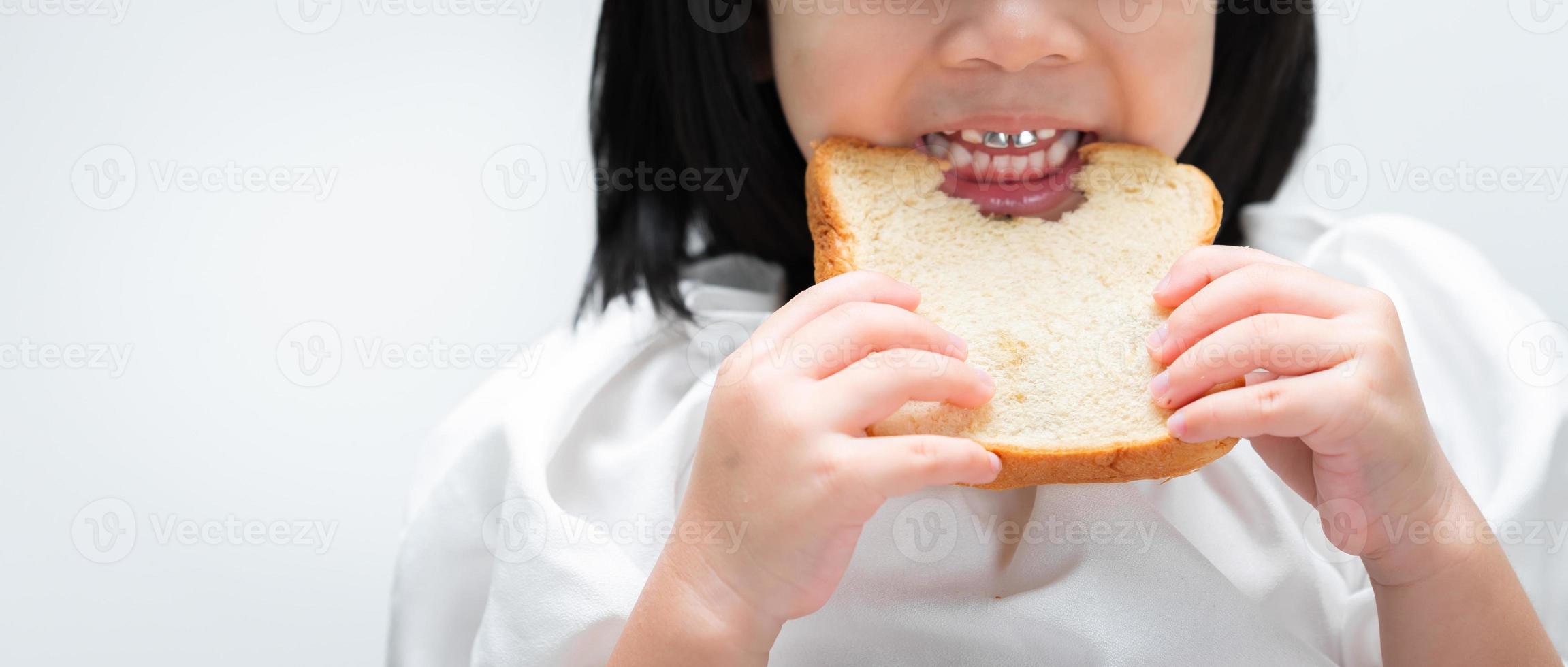 Nahaufnahme. Kinderhände halten das Brot, Kinderzähne sind Stückchen, die mit Begeisterung auf dem Brotlaib kauen. foto