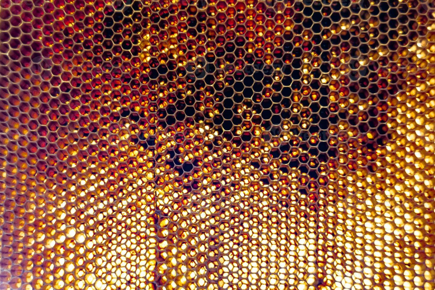 Tropfen Bienenhonig tropfen aus sechseckigen Waben, die mit goldenem Nektar gefüllt sind foto