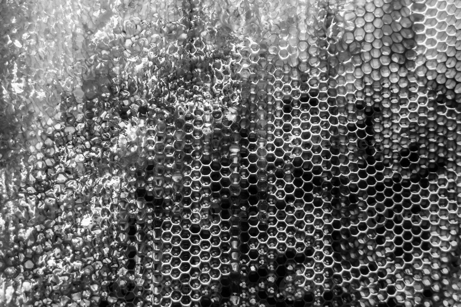 Tropfen Bienenhonig tropfen aus sechseckigen Waben, die mit goldenem Nektar gefüllt sind foto