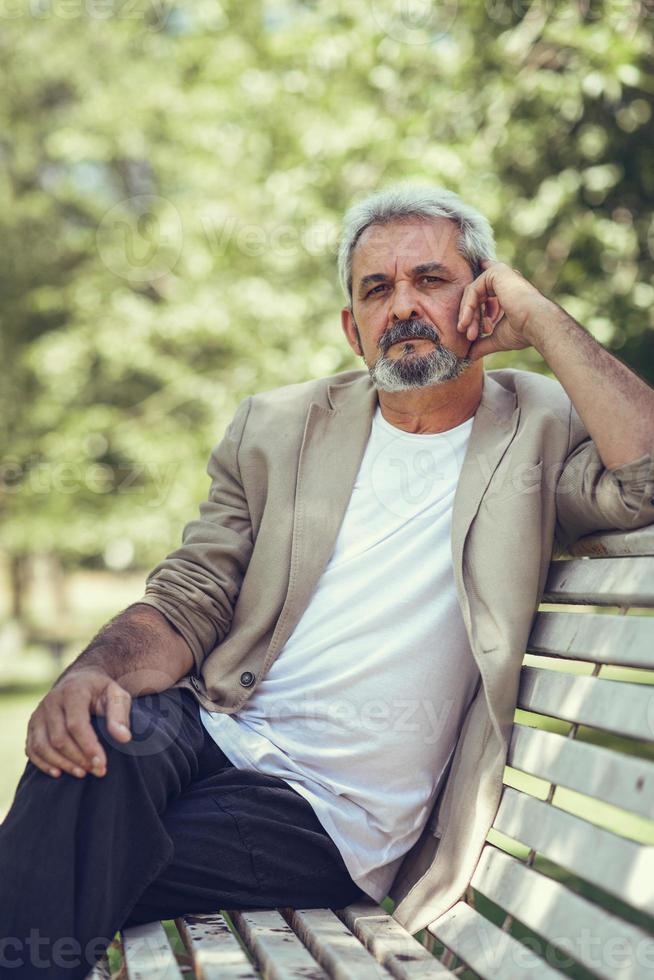 nachdenklich reifer Mann sitzt auf der Bank in einem Stadtpark. foto