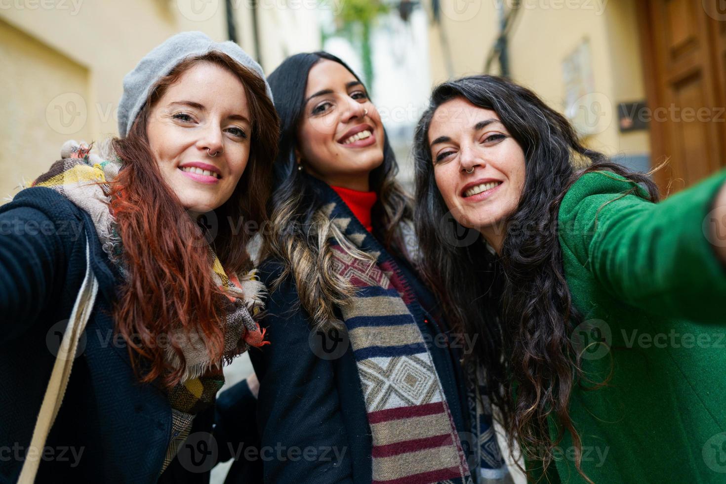 Gruppe von drei glücklichen Frauen, die zusammen draußen spazieren gehen foto