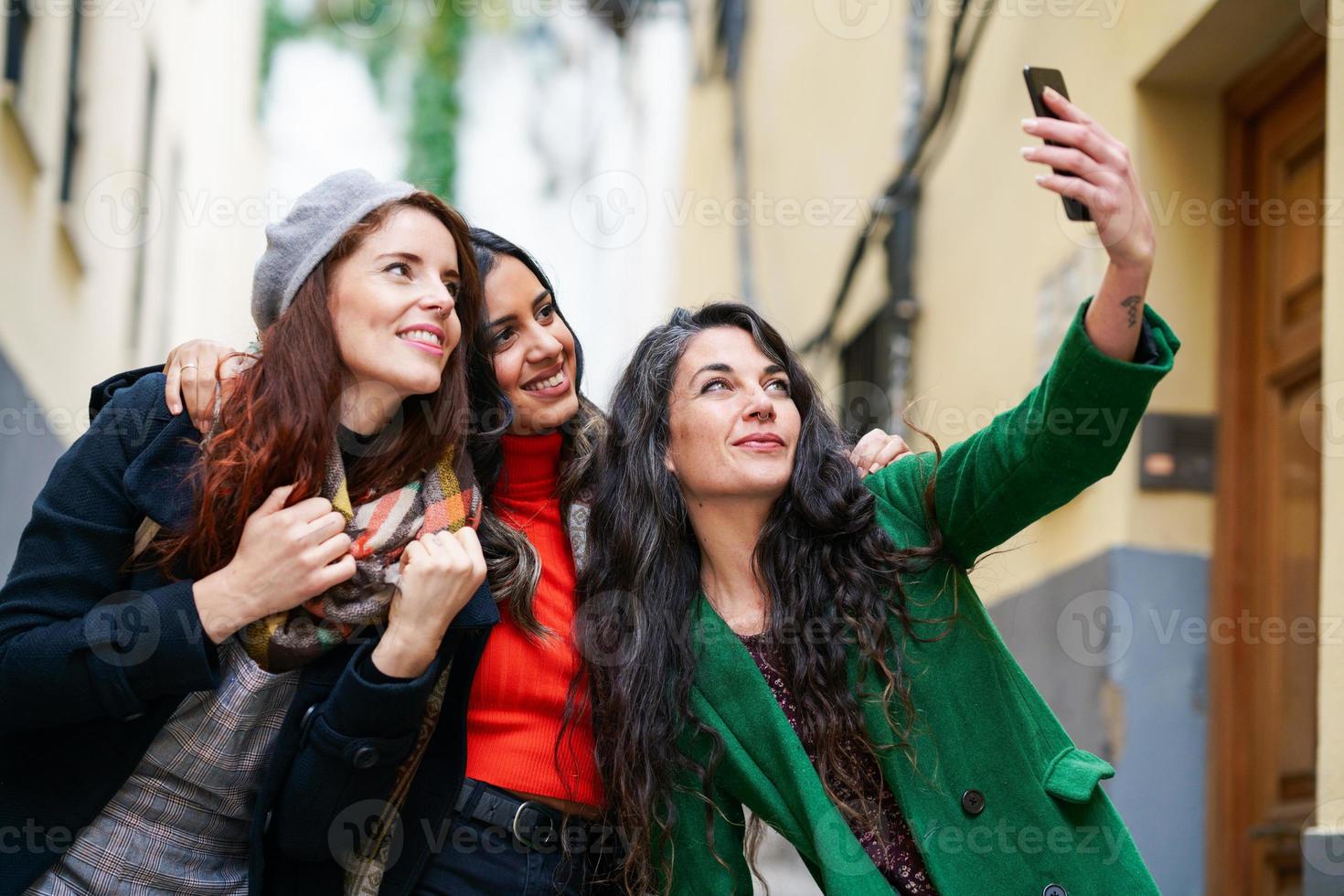 Gruppe von drei glücklichen Frauen, die zusammen draußen spazieren gehen foto