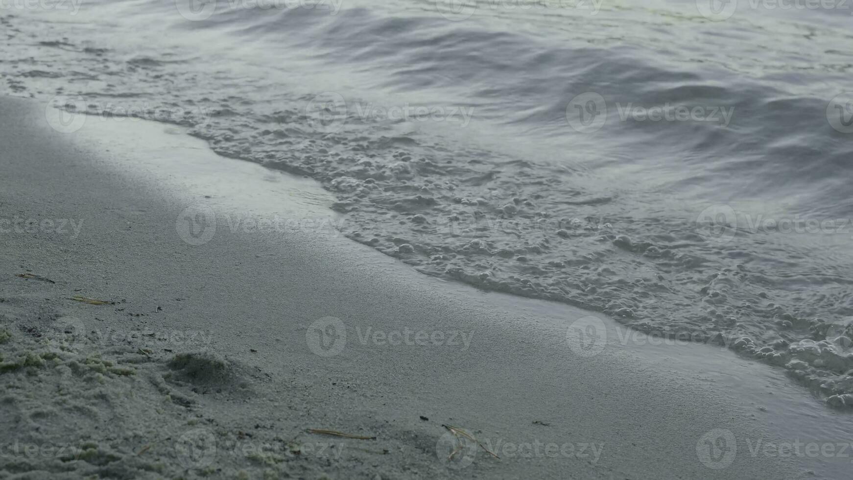 Sanft Welle von das Meer auf das sandig Strand. Nahansicht Detail von das schäumen Meer Wellen Waschen an Land beim das Strand foto