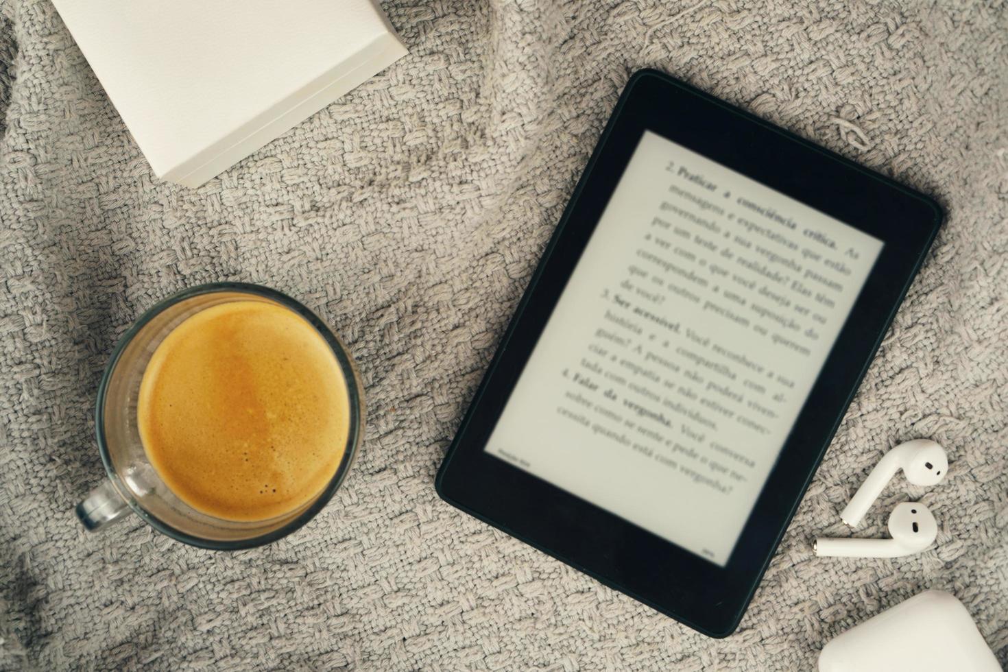 E-Book-Reader, eine Tasse Kaffee und ein Kopfhörer foto