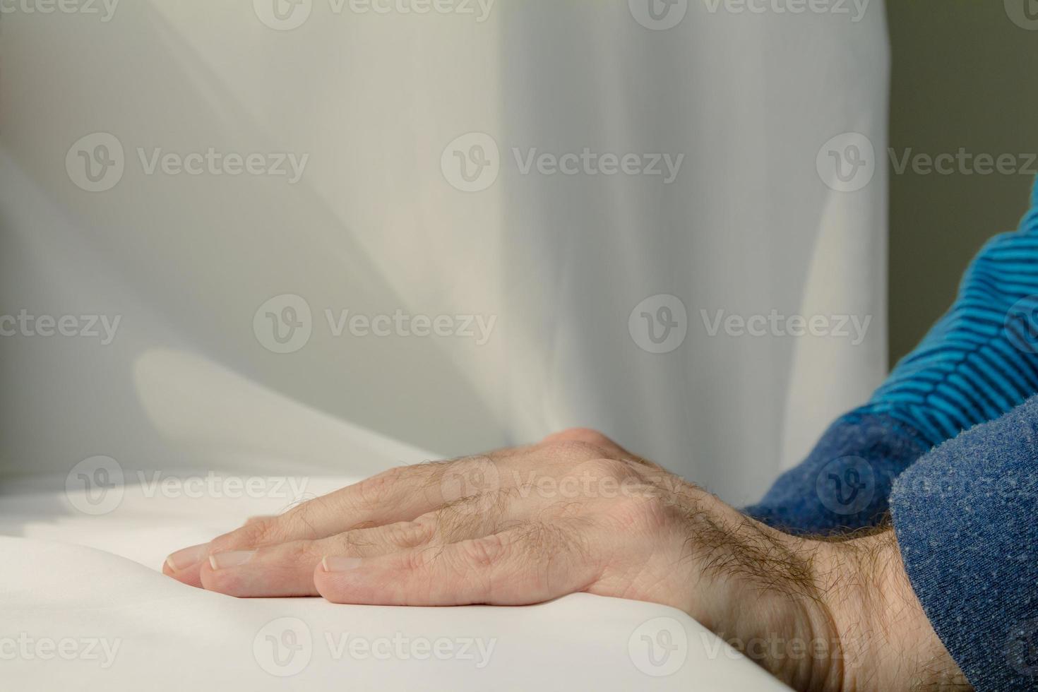 Mann lehnt sich und legt seine Hände auf weißen Stoffhintergrund foto