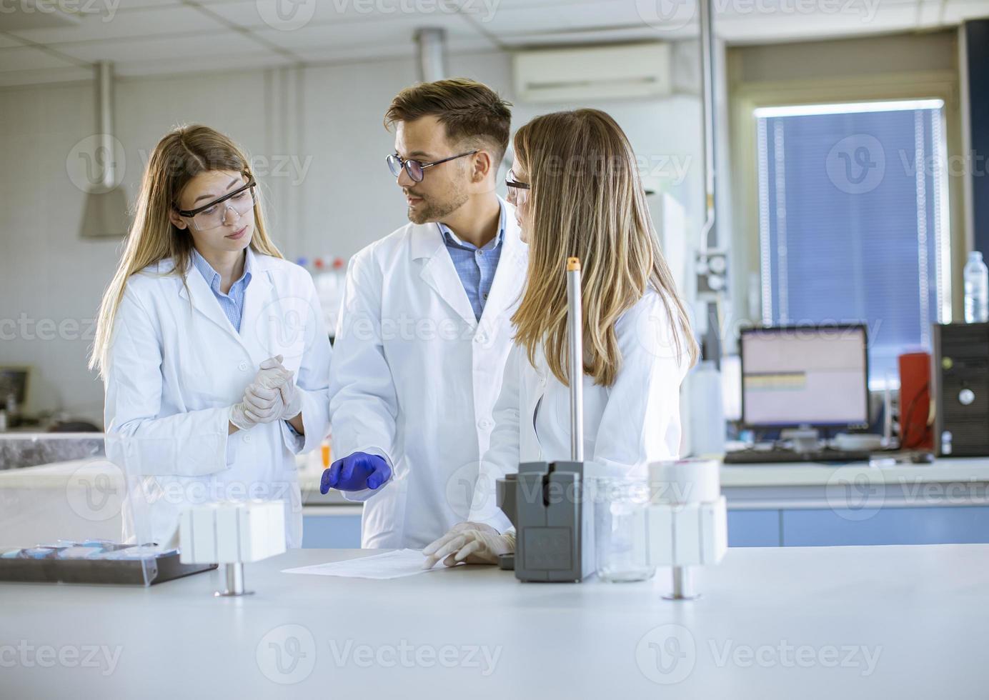 Forscher in Arbeitsschutzkleidung, die im Labor stehen und flüssige Proben an Ionenchromatographiegeräten analysieren foto