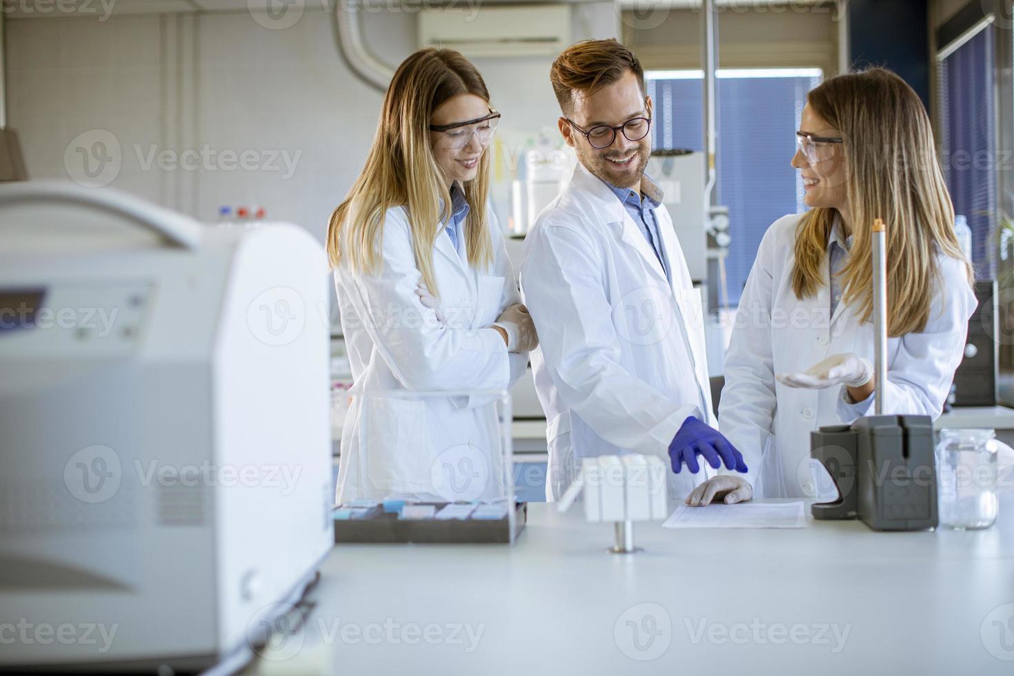 Forscher in Arbeitsschutzkleidung, die im Labor stehen und flüssige Proben an Ionenchromatographiegeräten analysieren foto