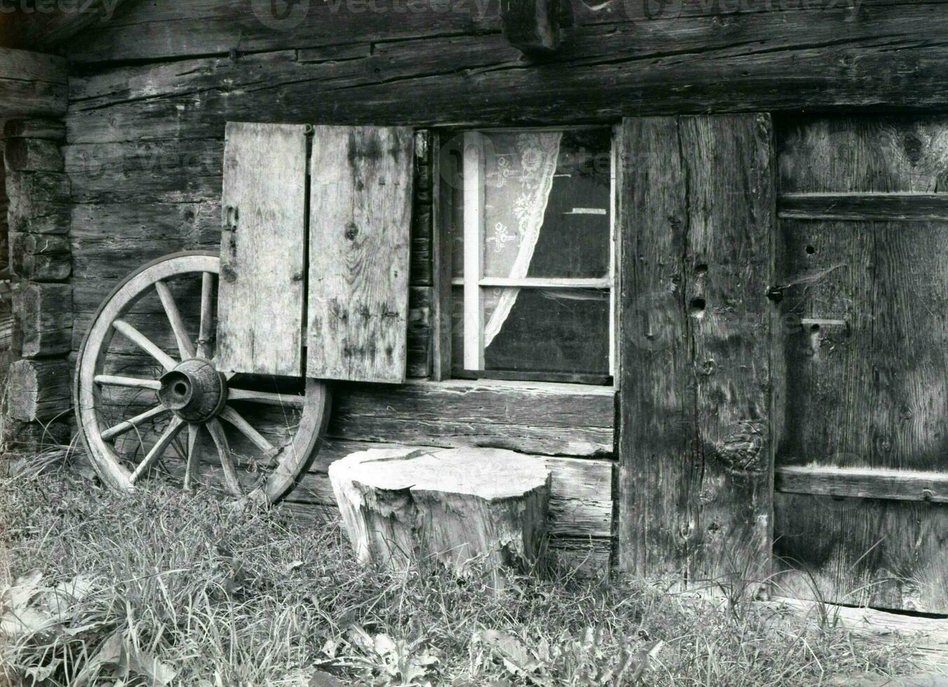 ein alt schwarz und Weiß Foto von ein Wagen Rad und Fenster