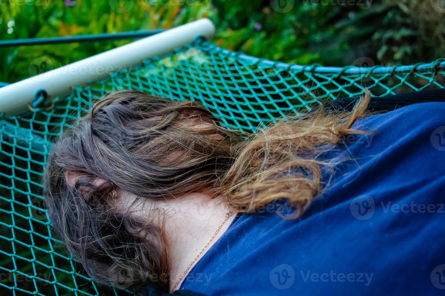 Frau liegt auf einer Hängematte und ihr Gesicht ist von ihren Haaren bedeckt foto