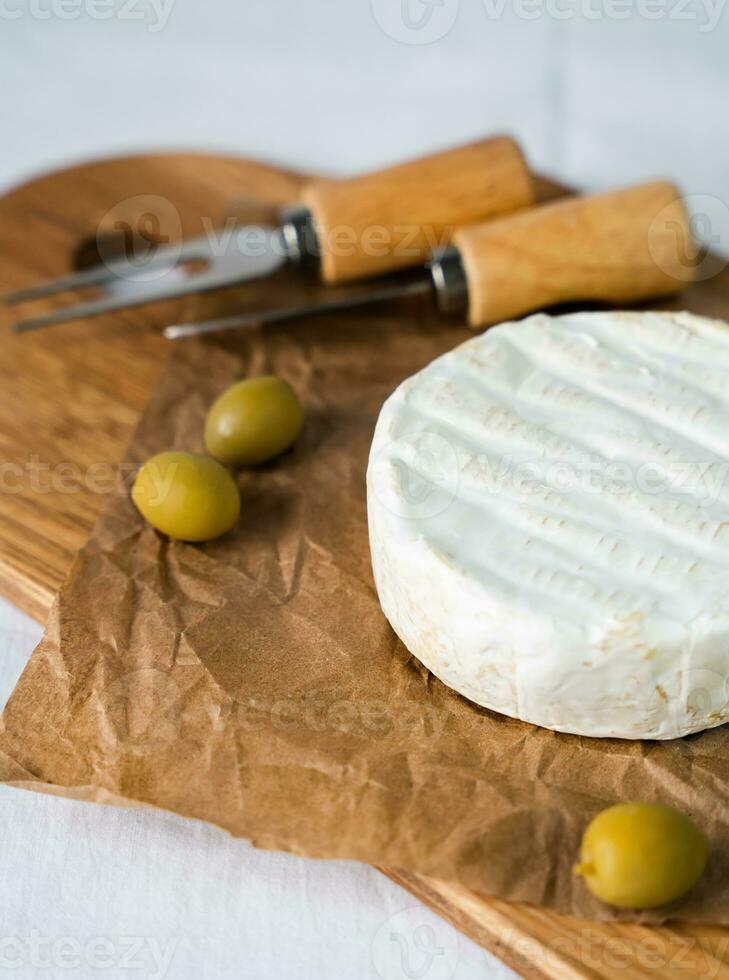 Camembert Käse, Oliven und Messer zum Schneiden auf ein hölzern Tafel. Nahansicht. selektiv Fokus. foto