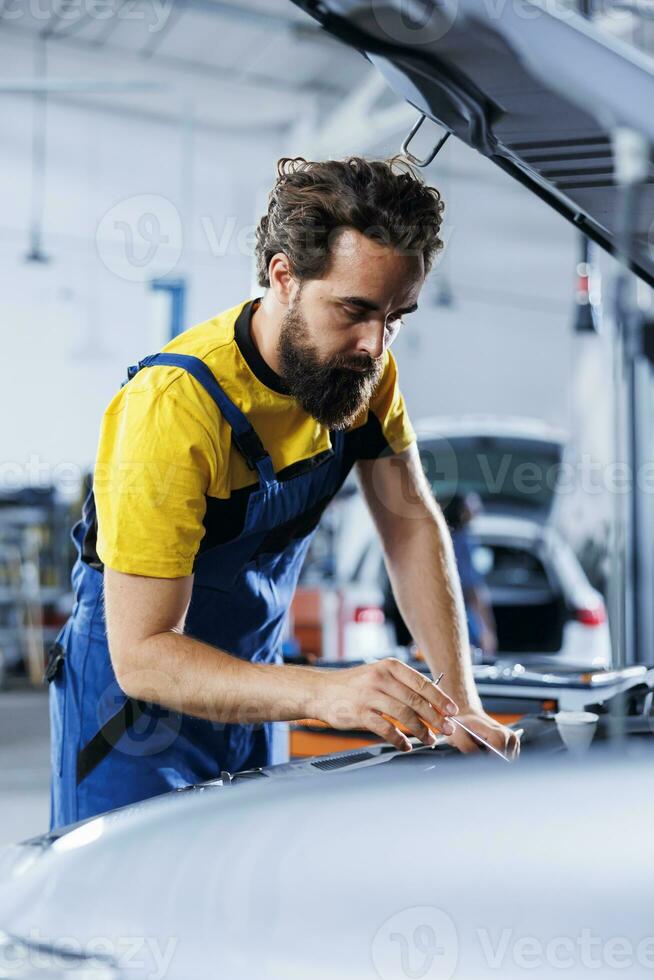 Ingenieur fachmännisch untersucht Treibstoff Panzer mit fortgeschritten mechanisch Werkzeug, gewährleisten optimal Automobil Performance und Sicherheit. erfahren Garage Arbeiter führt jährlich Fahrzeug Untersuchung foto