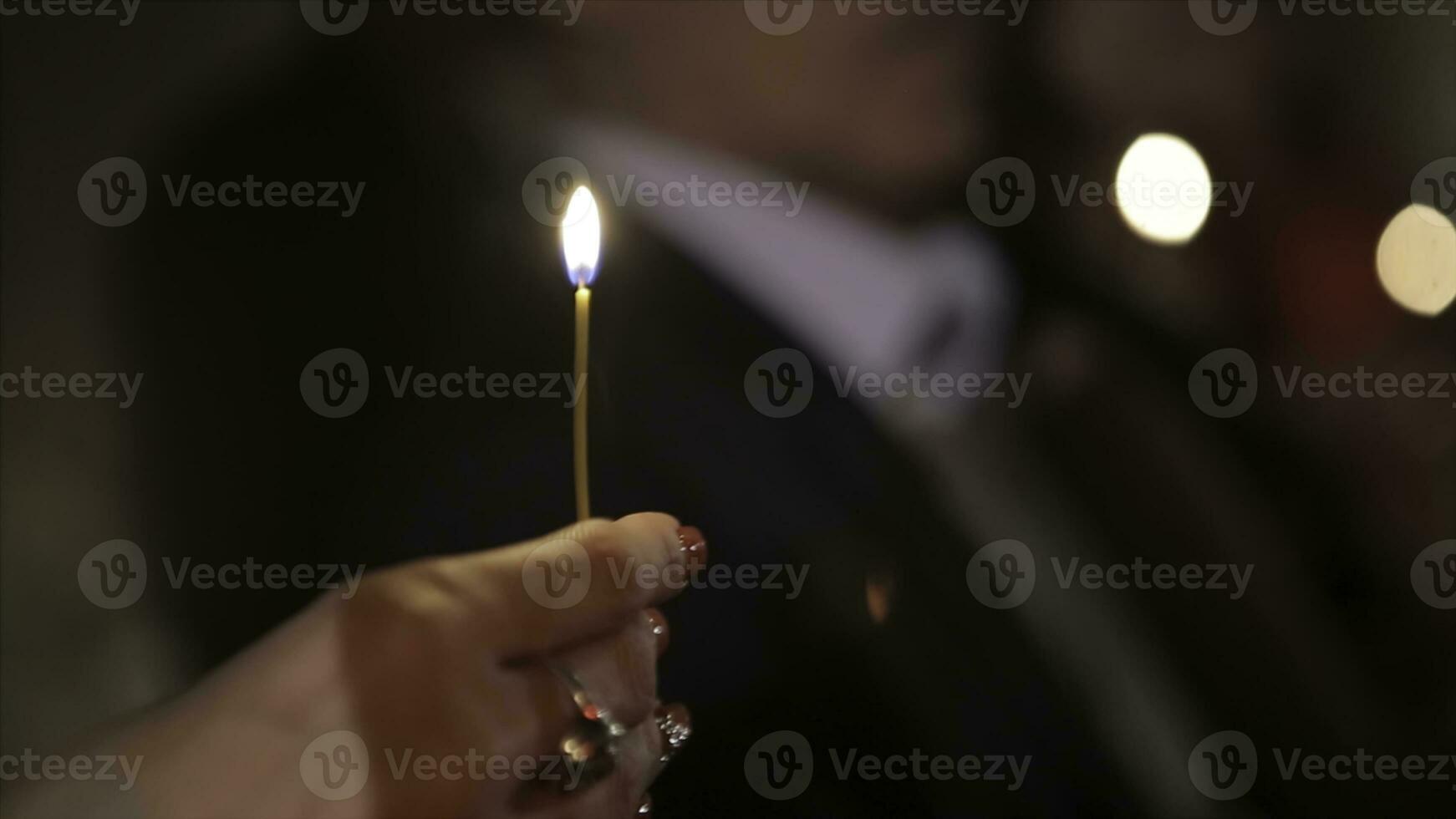 Beleuchtung ein Kerze mit ein Spiel zu erhalten ein romantisch Kerzenlicht. tolle andles und Kerzenhalter sind auf das Tisch. bleibe Beleuchtung mit das friedlich Hintergrund von religiös Zeremonie. foto