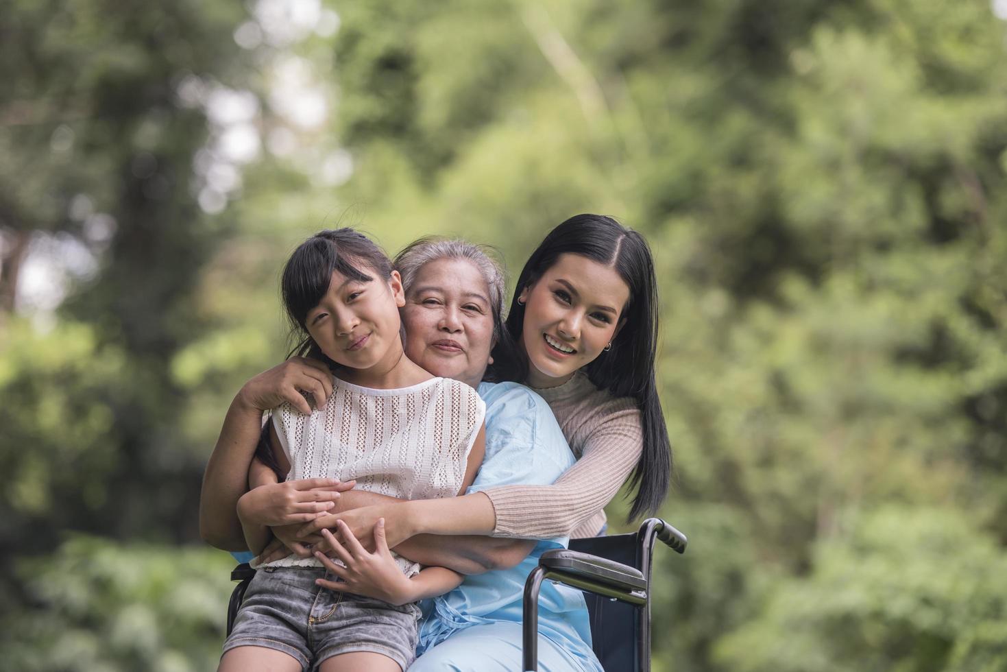 glückliche Großmutter im Rollstuhl mit ihrer Tochter und ihrem Enkel in einem Park, glückliches Leben glückliche Zeit. foto