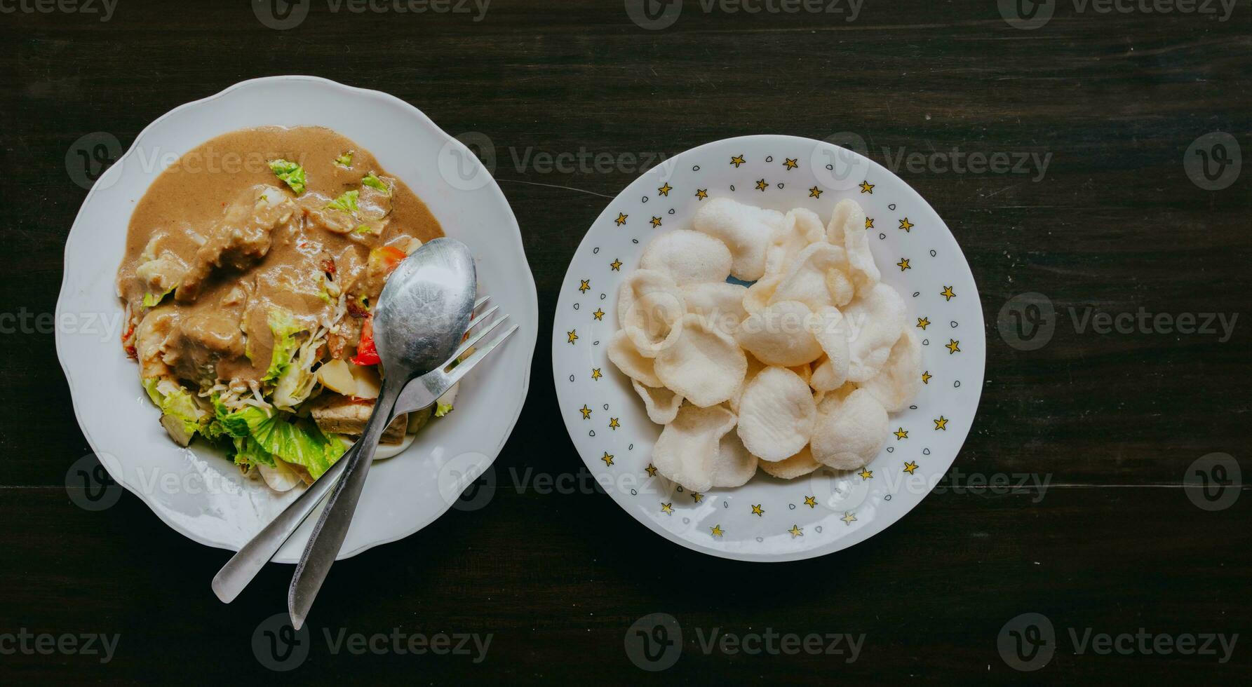 oben Aussicht von javanisch Gemüse Salat mit Erdnuss Soße Gado-Gado serviert mit Ei und Garnele Cracker. schwarz hölzern Hintergrund. foto