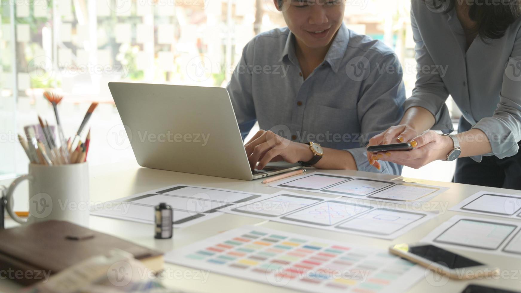 Ein Team von professionellen Designern arbeitet mit Smartphones und Laptops, um Anwendungen zu entwerfen. foto