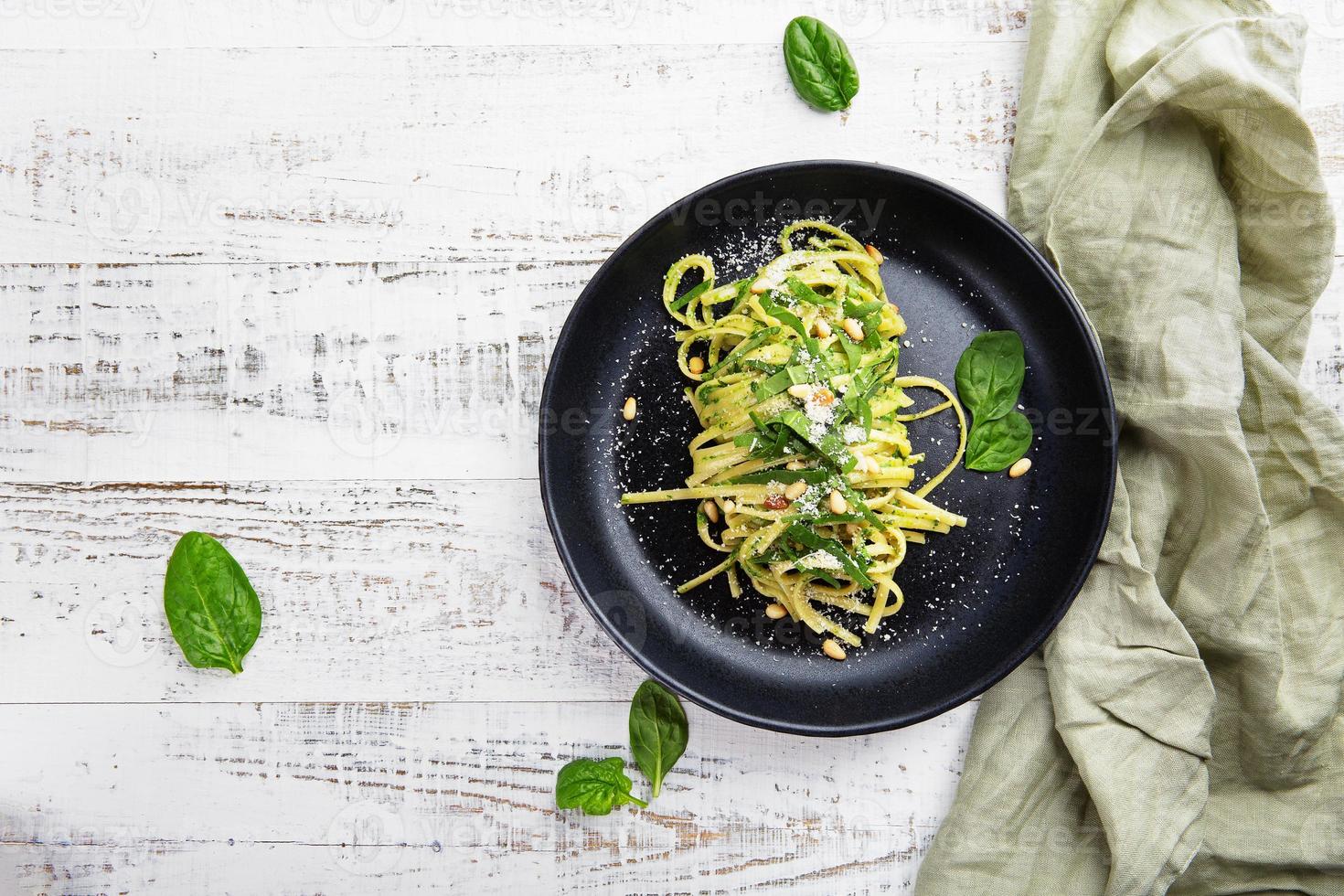 italienische Spaghetti mit Spinat, Pinienkernen und Parmesan auf hellgrauem Tisch foto