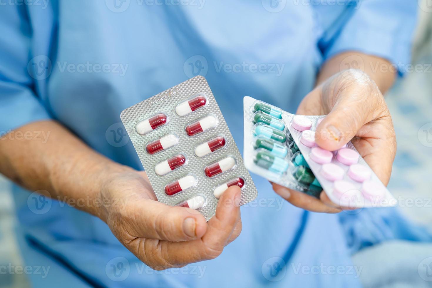 asiatische ältere Patientin, die Antibiotika-Kapselpillen in Blisterverpackung zur Behandlung von Infektionspatienten im Krankenhaus hält, Apotheken-Drogerie-Konzept. Konzept der Apotheke Drogerie. foto