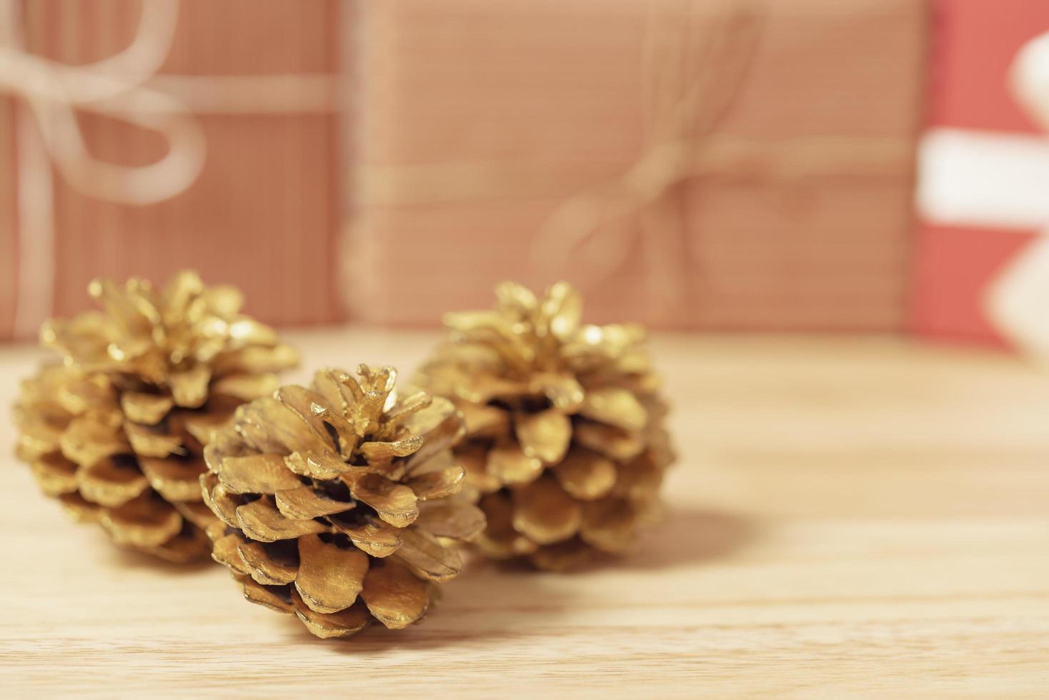 Goldene Tannenzapfen glitzerten Weihnachts- und Geschenkboxdekoration auf Holztischhintergrund. Platz kopieren. foto