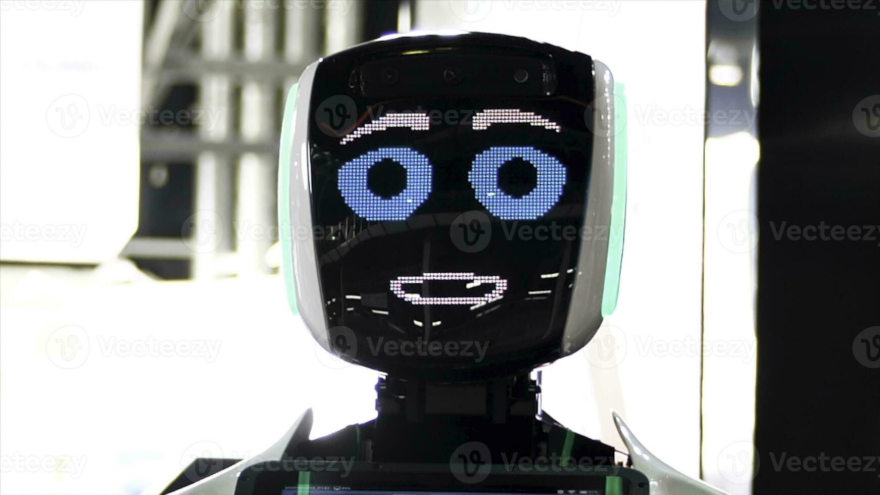 komisch Roboter mit groß Blau Augen lächelnd und reden. meida. schließen oben von Roboter Gesicht Bildschirm mit freundlich Lächeln beim das Ausstellung von modern Technologien. foto