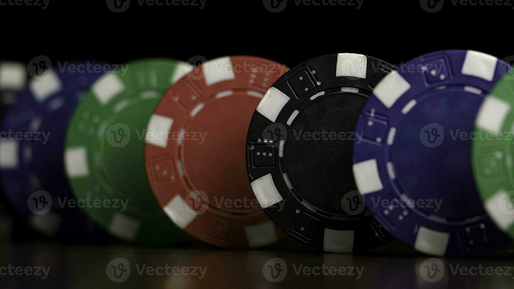 Poker Chips Stand im ein Reihe auf ein schwarz Hintergrund, ein Domino Wirkung. spielen Poker Chips sind auf das Tisch, ein Symbol von Kasino foto