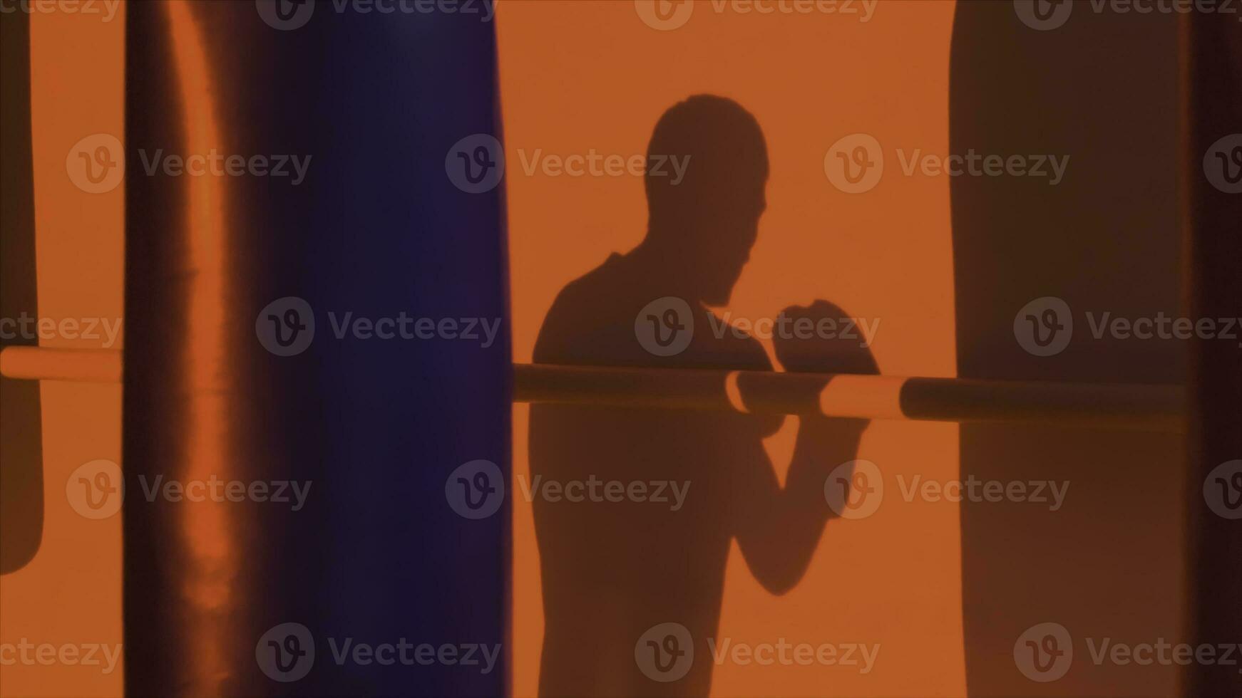 Silhouette oder Schatten von ein Boxer Stanzen ein Stanzen Tasche schließen hoch, rot Licht Hintergrund. Silhouette von jung männlich Boxer Schlagen Stanzen Tasche auf rot Hintergrund. Mann Athlet Stehen und Boxen. foto