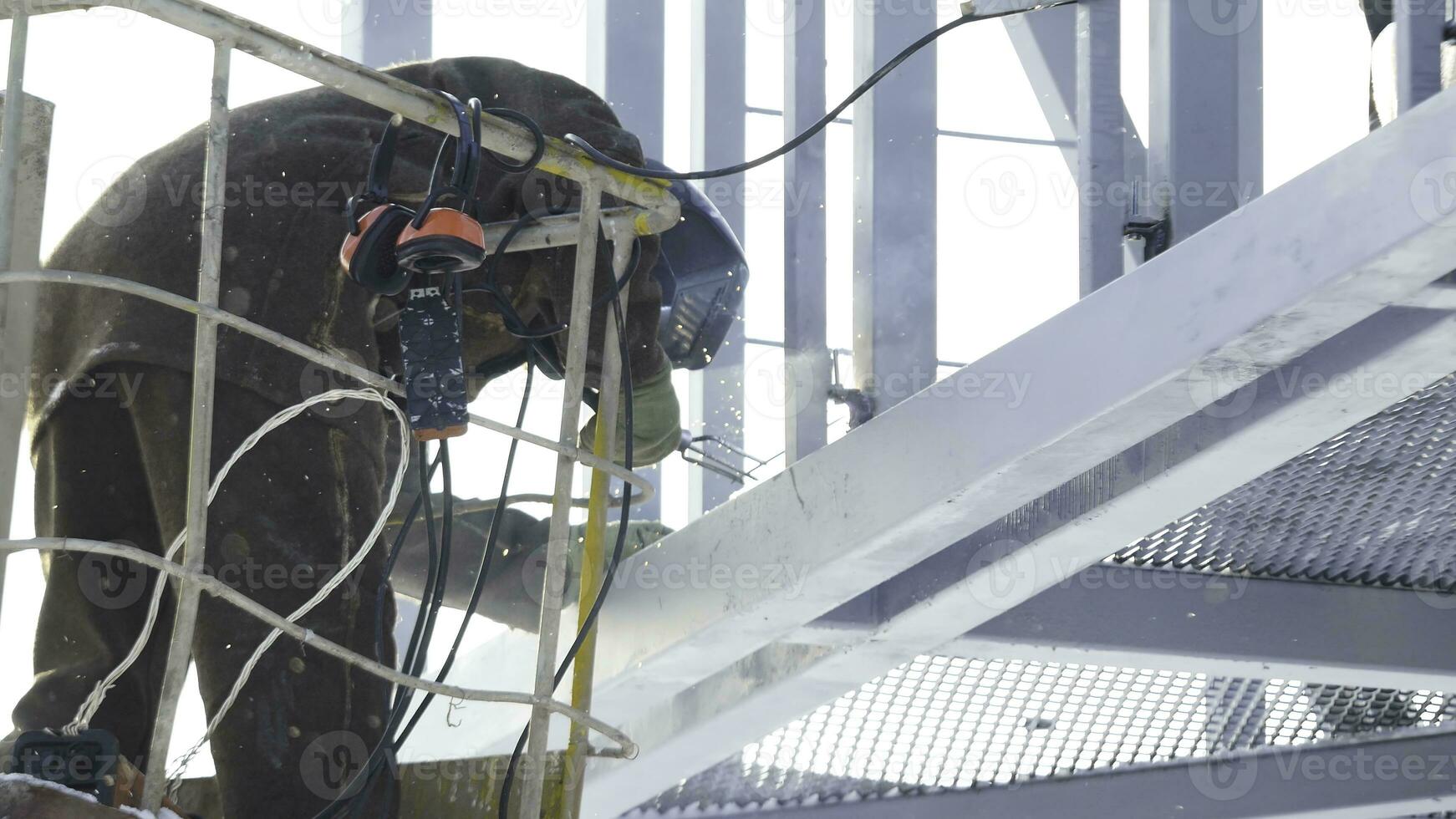 Schweißer Arbeiten mit Elektrode beim Bogen Schweißen im Konstruktion Seite? ˅ Winter draußen. Schweißer schützend Maske funktioniert draußen im Winter schließen oben foto