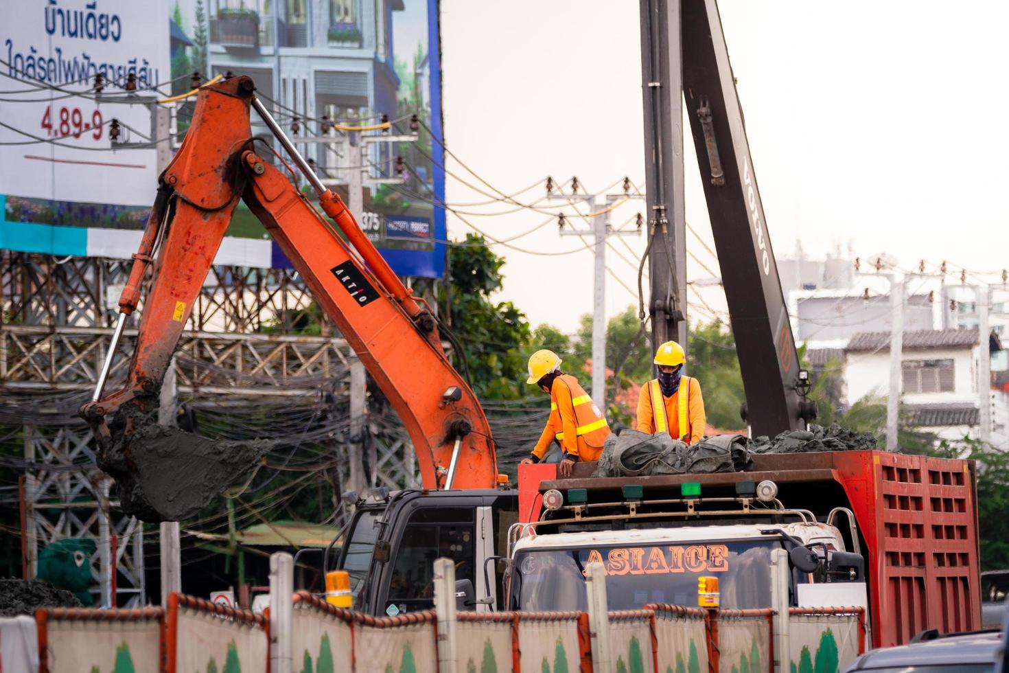 bangkok thailand 09.10.2019 - zwei vorarbeiter standen auf dem lkw, sie trugen gelbe helme, trugen orange langärmelige hemden zwei bagger arbeiten an großen industriemaschinen sicherheit bei der arbeit foto