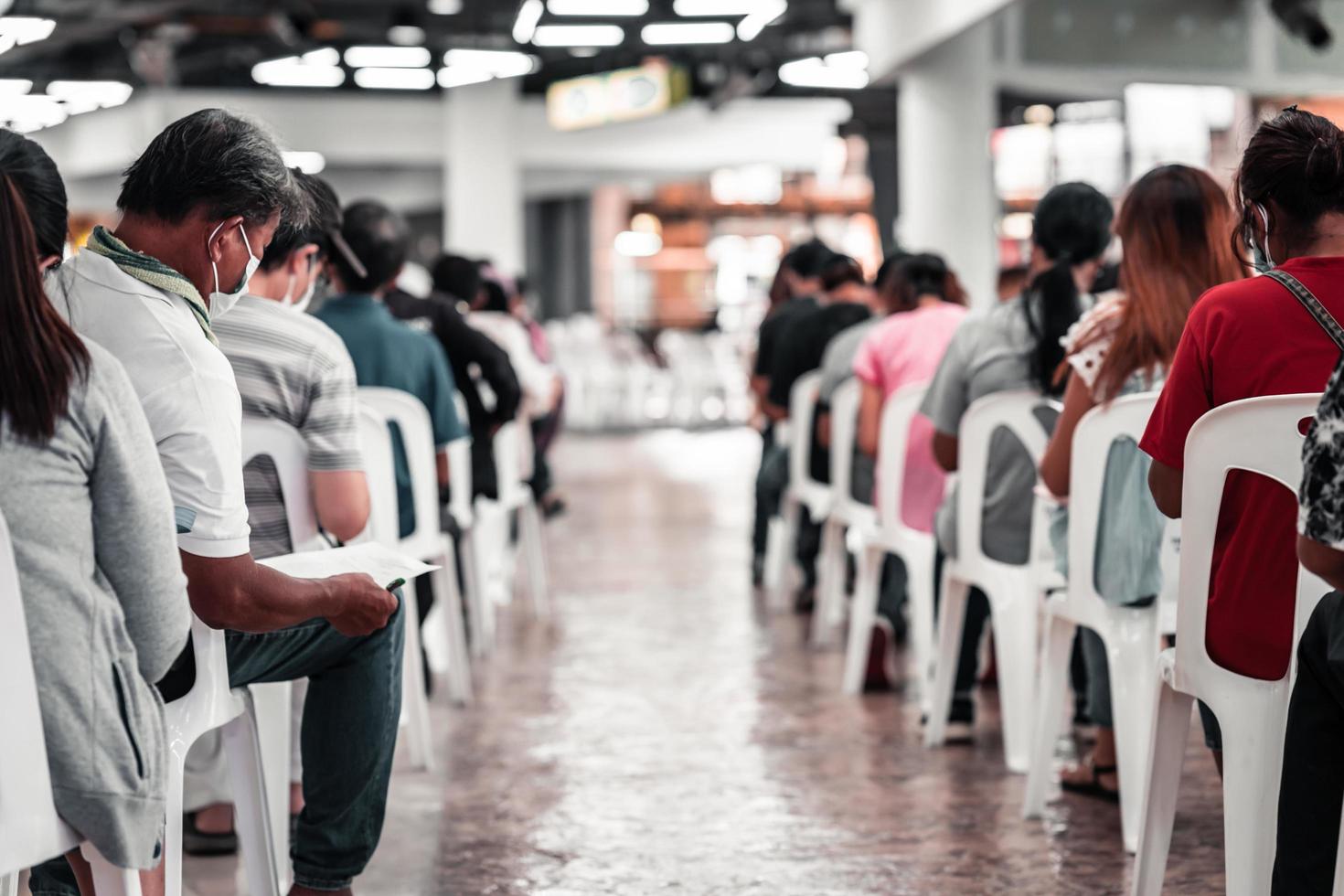 bangkok thailand 25. august 2021. menschen, die auf einem weißen stuhl sitzen und darauf warten, geimpft zu werden, um die ausbreitung der coronavirus-pneumonie covid-19 zu verhindern. foto