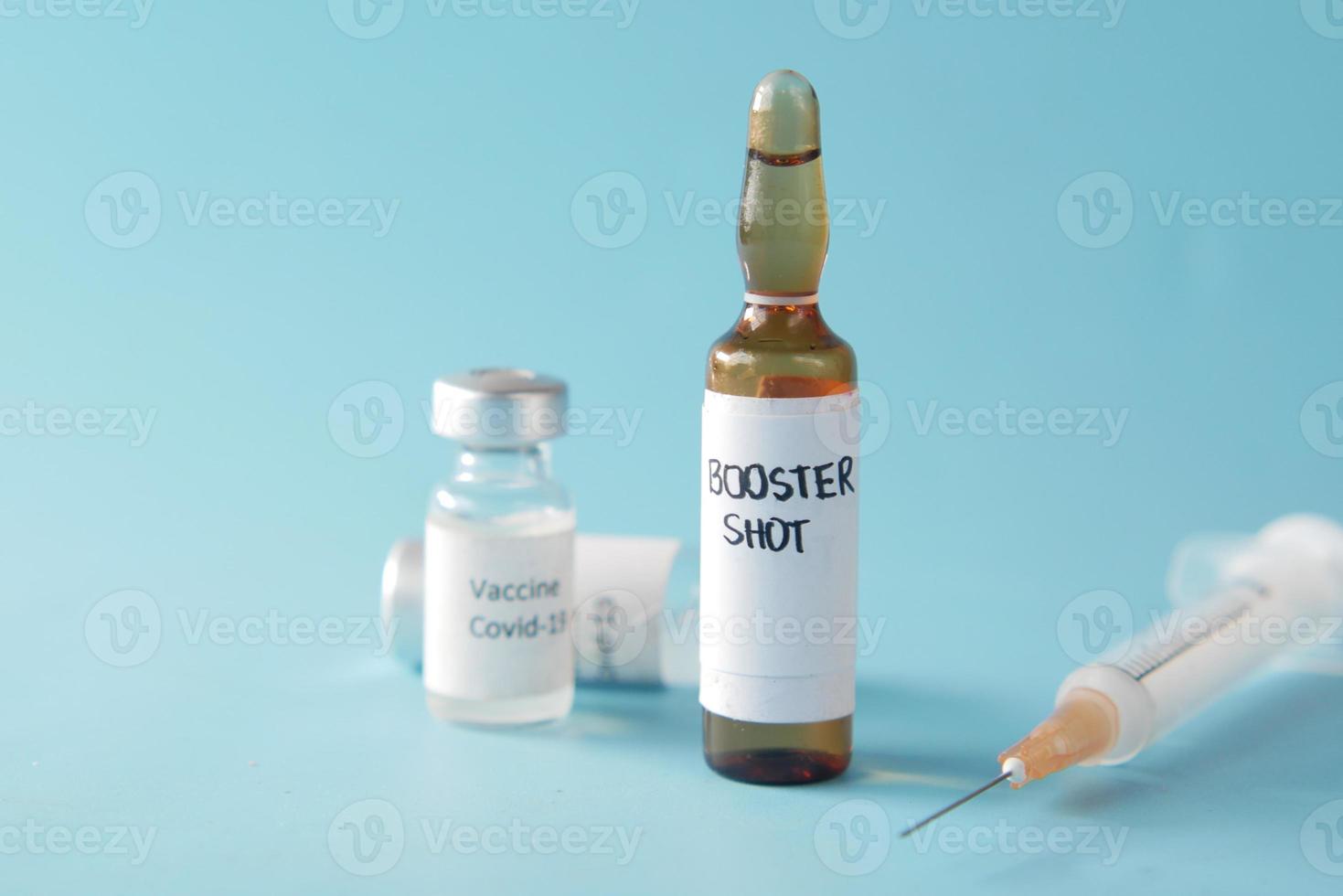 Booster-Schuss-Dosis-Coronavirus-Impfstoff und Spritze auf Blau foto