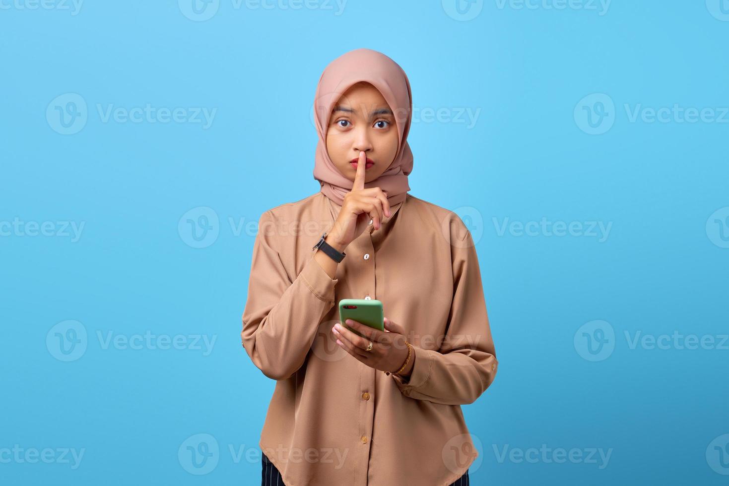 Porträt einer jungen asiatischen Frau, die ein Handy hält und mit den Fingern eine stille Geste macht foto