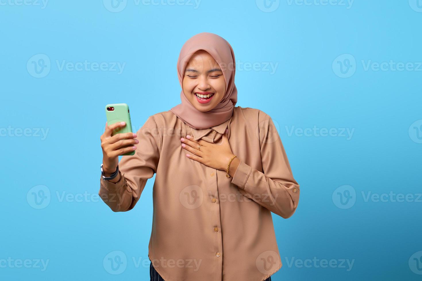 Porträt des Glücks junge asiatische Frau mit Handy mit einer anderen Hand auf der Brust foto