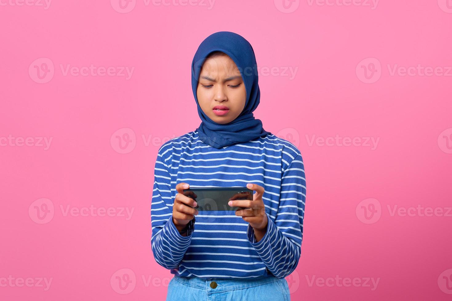 Porträt einer enttäuschten jungen Asiatin, die ein Videospiel auf dem Handy spielt foto
