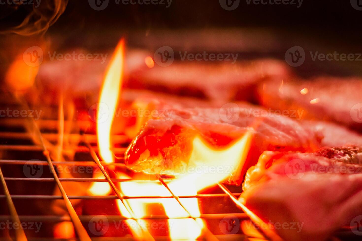 Grillen Schweinefleisch auf rostfrei Stahl Grill mit Flammen auf schwarz Hintergrund, Essen und Küche Konzept. Verbrennung Schweinefleisch auf ein Holzkohle Grill. foto