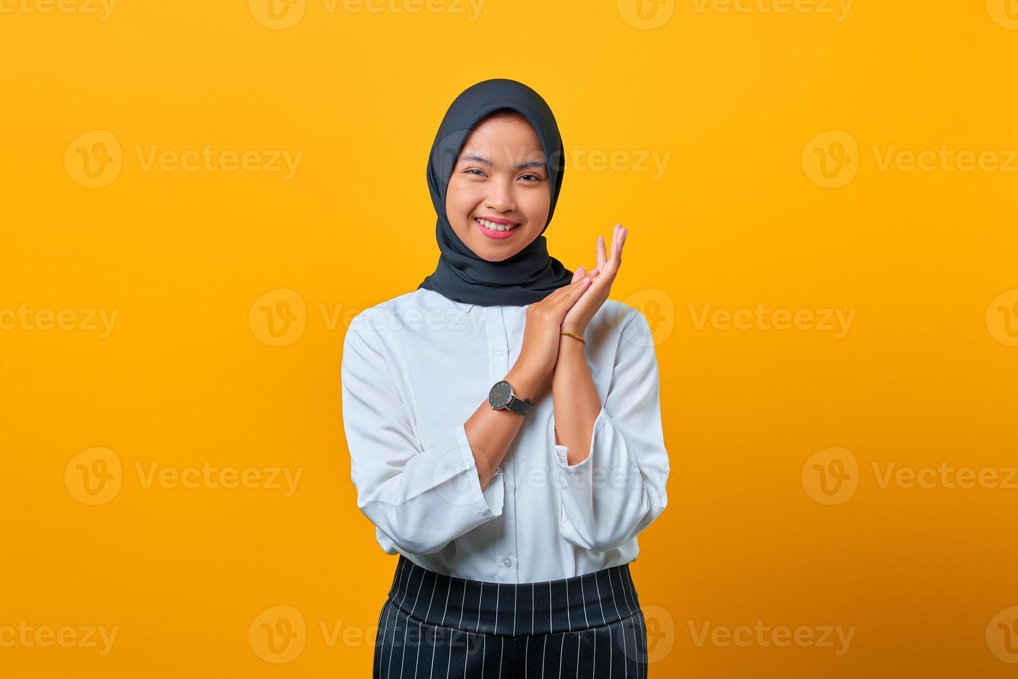 fröhliche schöne asiatische frau reibt handflächen und lächelt breit auf gelbem hintergrund auszudrücken foto