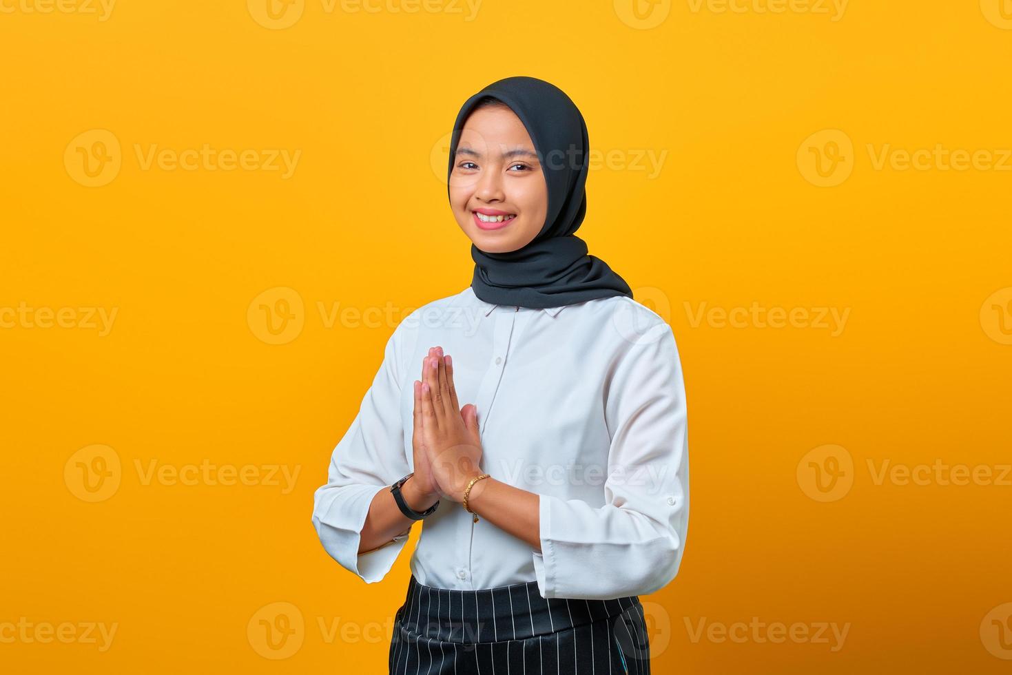 Porträt der lächelnden jungen asiatischen Frau Willkommensausdruck auf gelbem Hintergrund foto